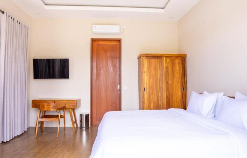 a bedroom with a white bed and a desk at Aditya House in Ubud