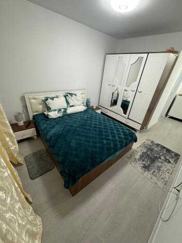 a bedroom with a bed with a green comforter and two mirrors at Garsoniera mobilata si utilata in Chiajna