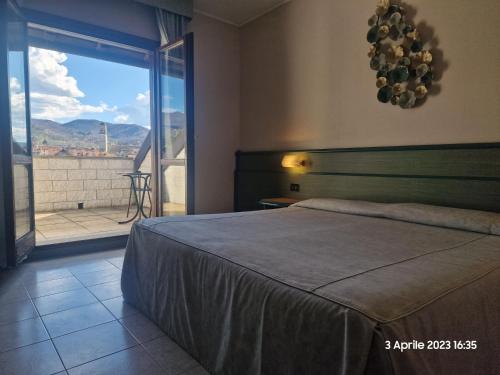 a bedroom with a bed and a view of a balcony at Hotel Pian del Sole in Sassello