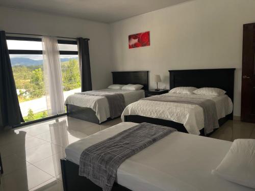 a hotel room with two beds and a large window at Diesbu Hotel in Marcala