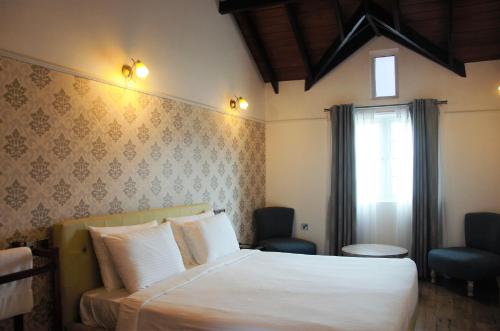a bedroom with a white bed and a window at Lakeside Cottages in Nuwara Eliya