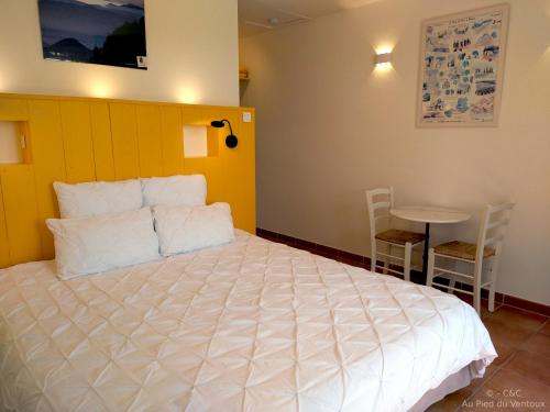 a bedroom with a large white bed and a table at AU PIED DU VENTOUX in Flassan