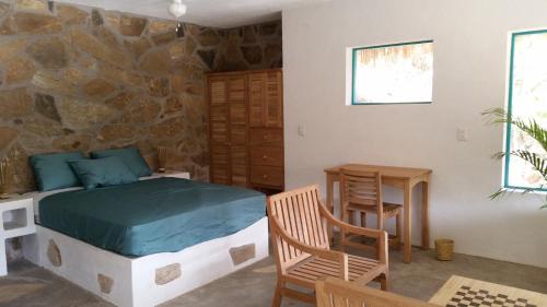 ein Schlafzimmer mit einem Bett, einem Tisch und einem Stuhl in der Unterkunft Casa Luna Playa in Puerto Ángel