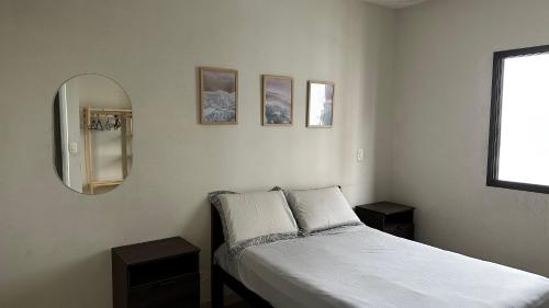 a small bedroom with a bed and a mirror at Apartamento Satel Praia in Itanhaém