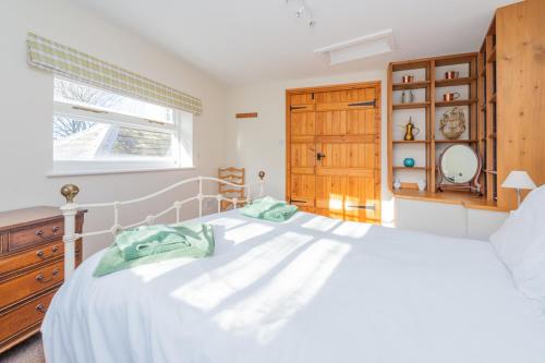 a bedroom with a white bed and a window at Kwerky Cottage in North Lydbury