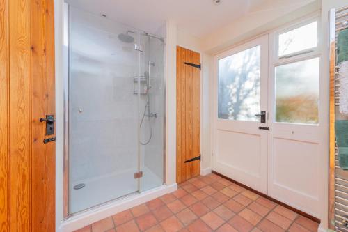 a bathroom with a shower with a glass door at Kwerky Cottage in North Lydbury