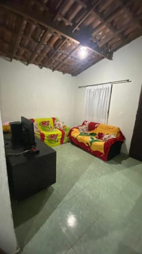 two beds in a room with a desk and a tv at Casinha no Sítio in Guaramiranga
