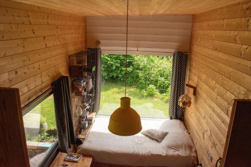 a bedroom in a tiny house with a large window at Tiny house gite bucolique Brocéliande Hébergement insolite et centre bien être in Saint-Brieuc-de-Mauron