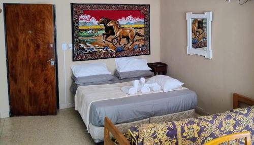 a bedroom with two beds and a painting on the wall at Alas termas in Termas de Río Hondo