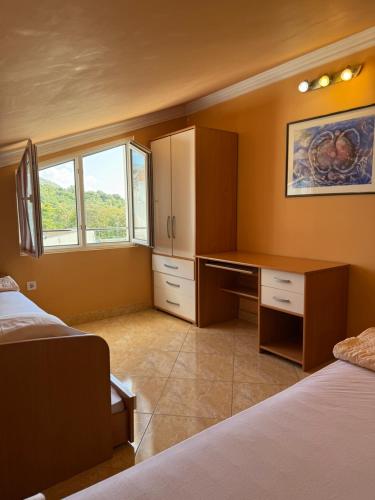 a bedroom with two beds and a desk and a window at Apartments Nikitenko Meljine in Meljine