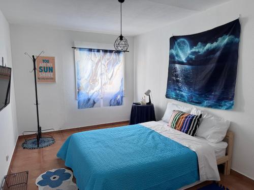 a bedroom with a blue bed and a painting on the wall at Traditional Peniche House in Peniche