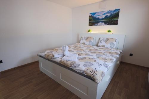 a white bed in a bedroom with a picture on the wall at M&M apartma in Bohinj