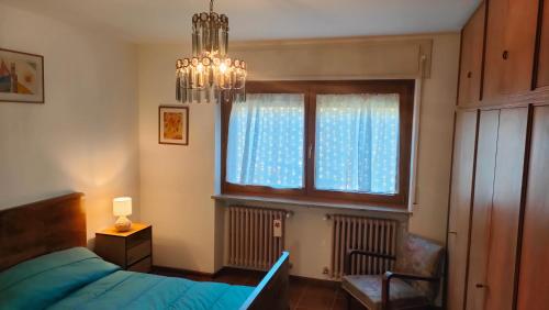 a bedroom with a bed and a chandelier and a window at Casa Vallina - Garden & Mountain View in Castion