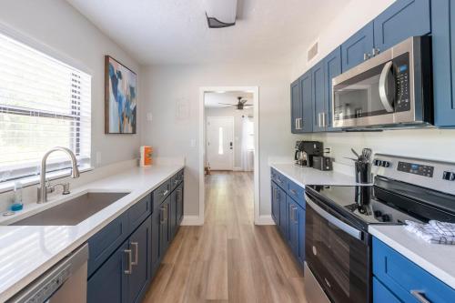 a kitchen with blue cabinets and a sink and a microwave at The Pineapple Express in Orlando