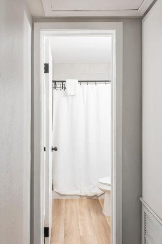 a bathroom with a white shower curtain and a toilet at The Pineapple Express in Orlando