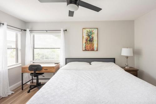 a bedroom with a bed and a desk and a fan at The Pineapple Express in Orlando