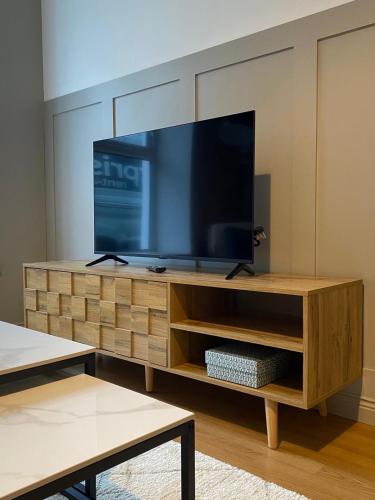 a living room with a large television on a wooden entertainment center at The Old Shop Apartment in Rathmullan