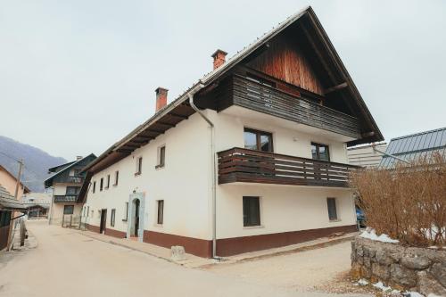 a large white building with a wooden roof at M&M apartma in Bohinj