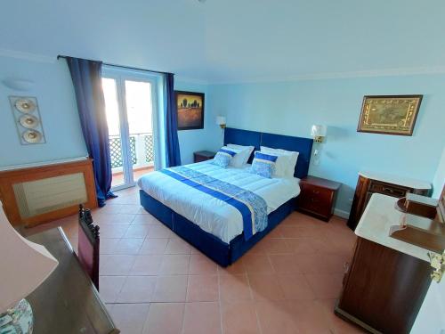 a blue bedroom with a bed and a balcony at Estalagem De Colares in Sintra