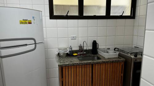 a kitchen with a sink and a refrigerator at Apartamento Satel Praia in Itanhaém