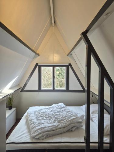 a bed in a loft with a window at Bois d' Hibou in Durbuy