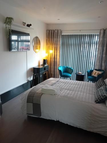 a bedroom with a large bed and two blue chairs at The Snug on The Brae in Inverness