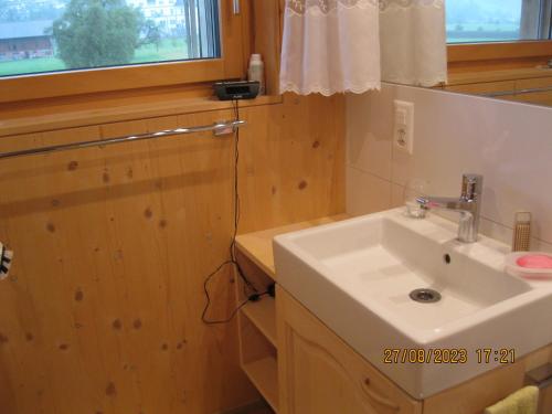 a bathroom with a white sink and a window at Holz100 Zimmer mit Rigiblick in Steinen