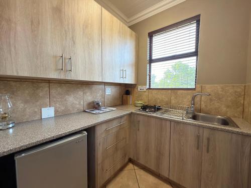 a kitchen with wooden cabinets and a sink and a window at My Africa Adventure Farm in Hoedspruit