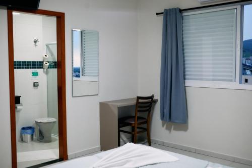 a bedroom with a bed and a desk and a chair at Hotel Beirut in Aparecida