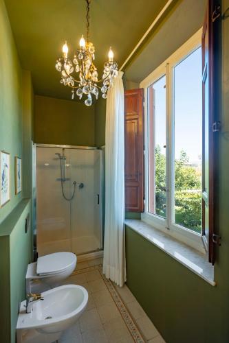 a bathroom with two toilets and a window and a chandelier at il buen retiro in Lucca