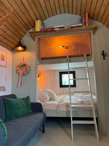 a bedroom with a bunk bed and a couch at Żuławska Zielona Przystań, całoroczny domek na kołach Sikorka in Izbiska