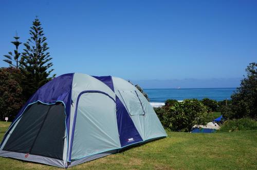 a tent sitting on the grass next to the ocean at Fitzroy Beach Holiday Park in New Plymouth