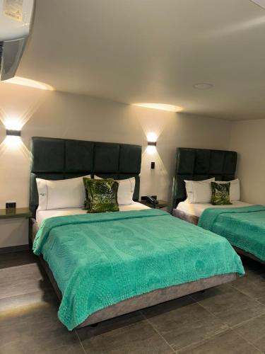 a bedroom with two beds with green sheets and pillows at Hotel Green Gold in Bucaramanga
