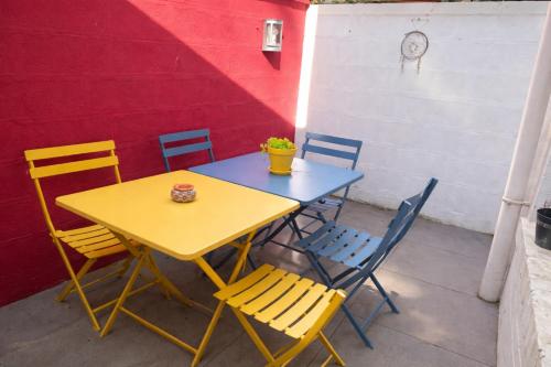 a yellow table and chairs sitting next to a red wall at Maison spacieuse au coeur du Centre - Plage à pied in Luc-sur-Mer