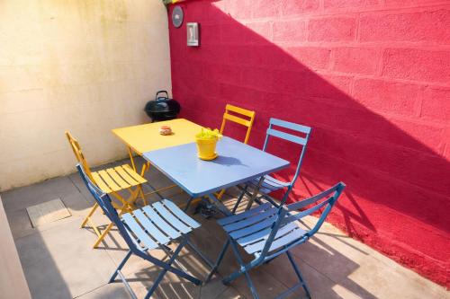a table with four chairs and a red wall at Maison spacieuse au coeur du Centre - Plage à pied in Luc-sur-Mer
