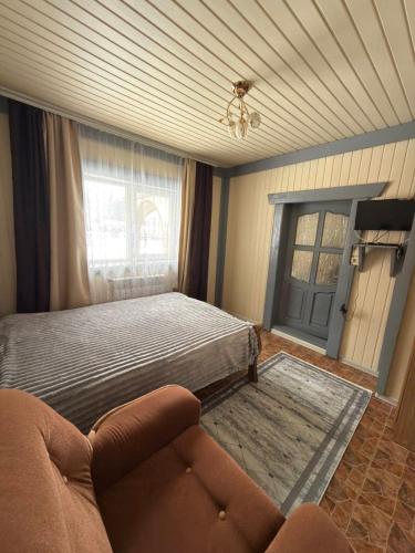 a bedroom with a bed and a couch and a window at Садиба у "Степана" in Synevyrsʼka Polyana