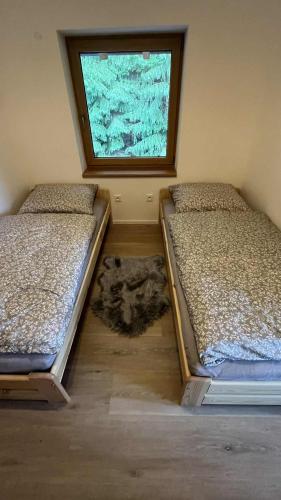 two beds sitting in a room with a window at Apartmán #7 Mariánská Hora in Albrechtice v Jizerských horách