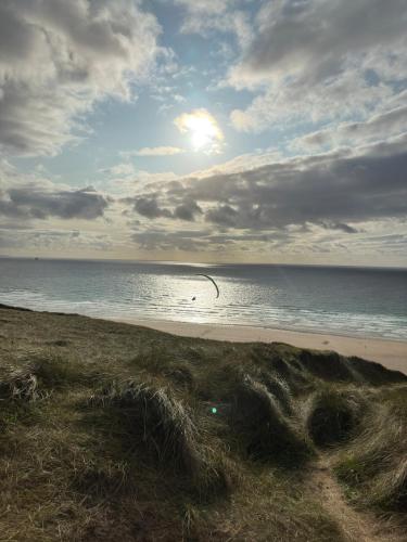 a beach with the ocean and a cloudy sky at Perranporth Beach 3 Bed Holiday Home Cornwall. in Perranporth