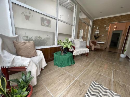 a living room with white furniture and a green table at Vida & Brisa Pousada in Pelotas