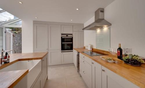 a kitchen with white cabinets and wooden counter tops at Modern & homely 2-bed - close to BEACH in Bideford