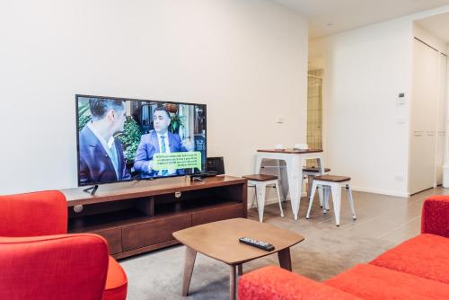 a living room with a large flat screen tv at Comfort Apartments Box Hill in Box Hill