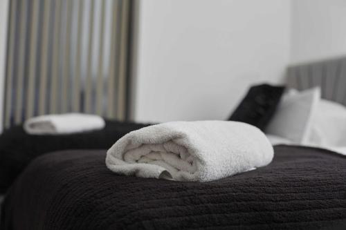 a white towel sitting on top of a bed at Hayy Apartments Stylish & Central Stays in Barnsley in Barnsley