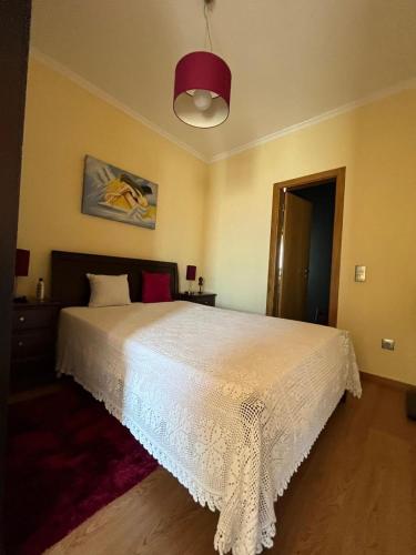 a bedroom with a white bed and a red light at Daisy Country House in Lousada