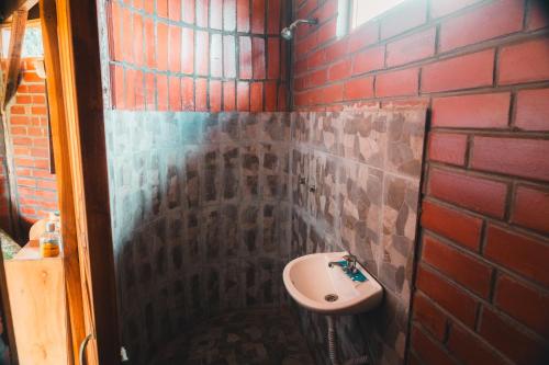 a bathroom with a sink and a brick wall at COTOPAXI Wasi Andina Lodge in Latacunga