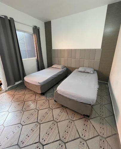 two beds in a room with a tiled floor at Studios Mattigor - ao lado da Dutra em Caçapava-SP in Caçapava