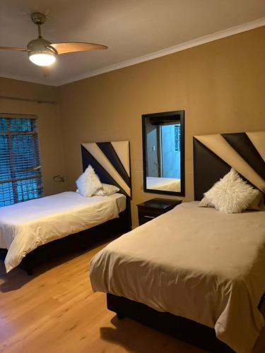 a bedroom with two beds and a mirror on the wall at Swakhanya Haus in Vereeniging