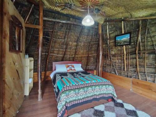 a bedroom with a bed in a straw hut at COTOPAXI Wasi Andina Lodge in Latacunga