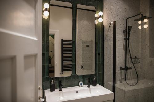 a bathroom with a sink and a shower and a mirror at Apartament Wspomnień in Zamość