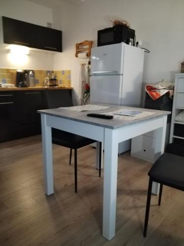 a white table in a kitchen with a refrigerator at Lo Cantalés d’Aubrac in Laguiole