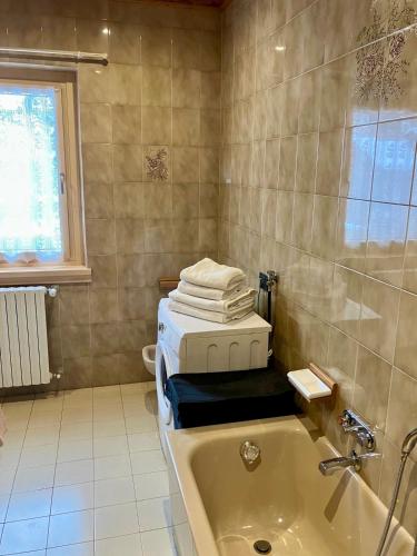 a bathroom with a tub and a stack of towels at Baita Azzurro in Isolaccia